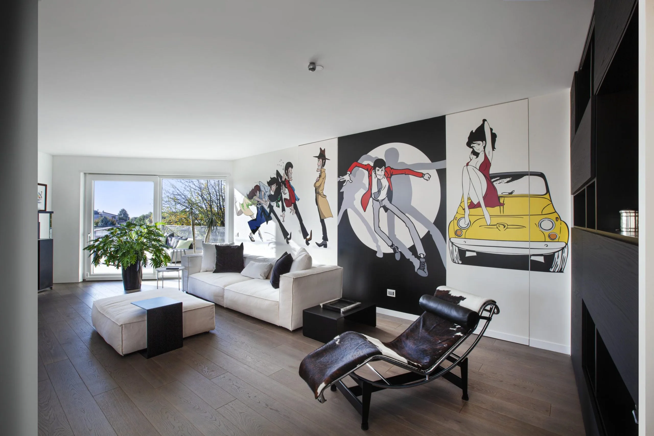 Soggiorno con divano chiaro, chaise longue e parete decorata con illustrazioni